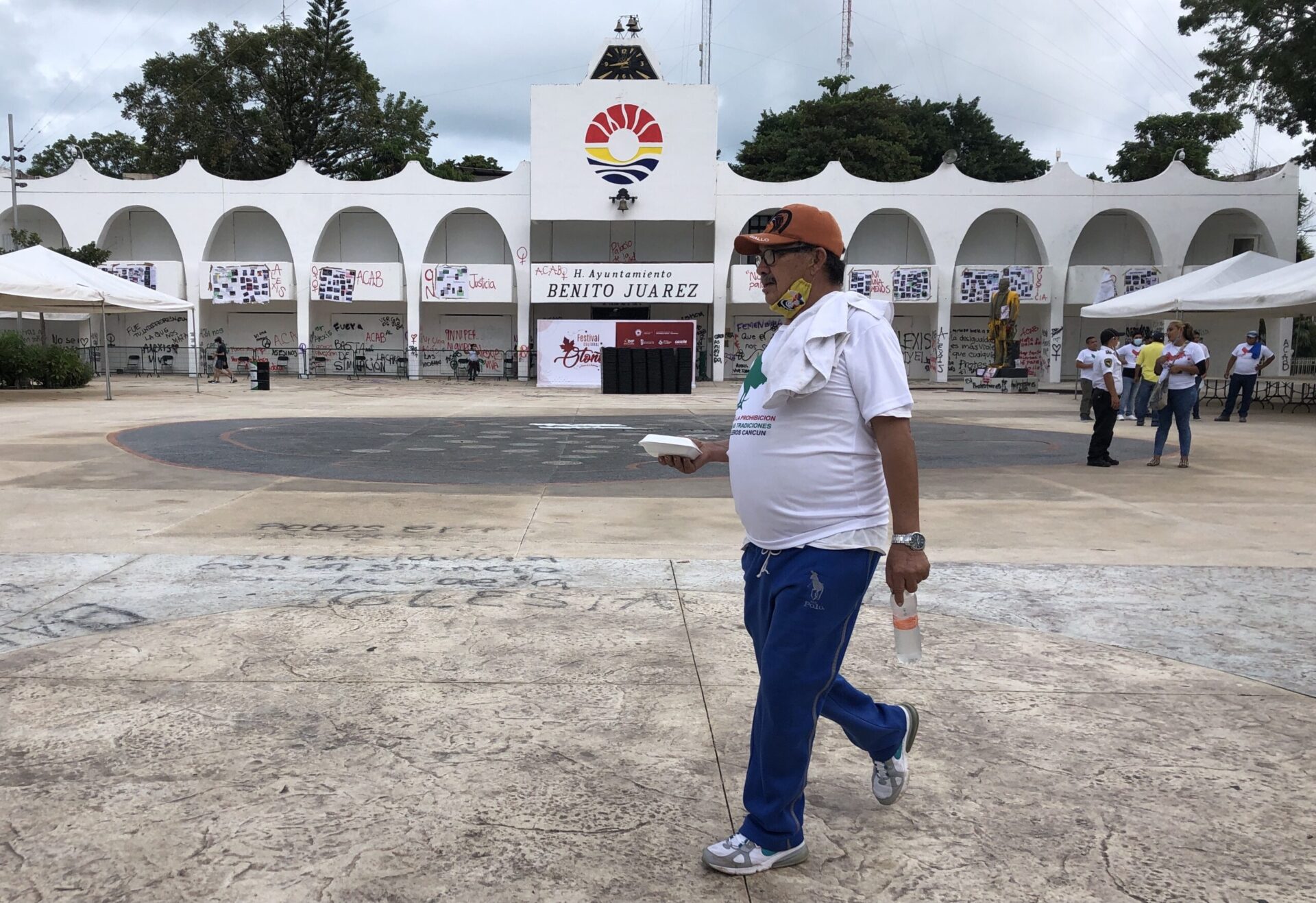 Hombre caminando frente a palacio municipal de Cancún